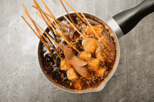 a pot filled with skewers of food and sauce