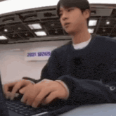 a man is typing on a laptop computer while sitting at a table .