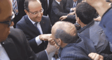 a man in a suit and tie shakes hands with another man in a crowd