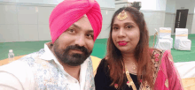 a man wearing a pink turban poses with a woman in a pink dress