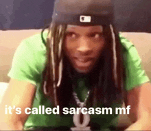 a man with dreadlocks and a hat is sitting on a couch and saying it 's called sarcasm mf