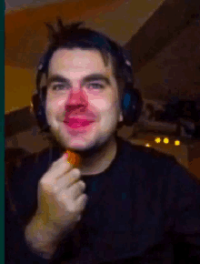 a man wearing headphones has a red nose and is eating something