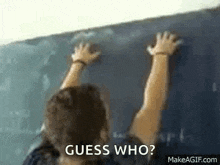 a person is standing in front of a blackboard with their hands up .