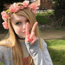 a girl wearing a flower crown is giving a peace sign