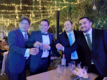 a group of men in suits and ties are toasting with shot glasses