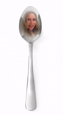 a silver spoon with a reflection of a woman in it