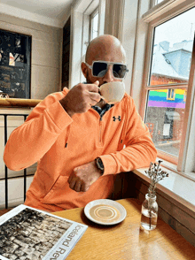 a man drinking a cup of coffee while sitting at a table with a magazine that says iceland revival