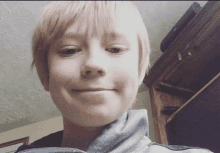 a young boy with short blonde hair is smiling for a picture