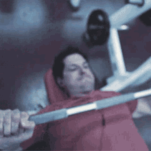 a man in a red jacket is lifting a barbell