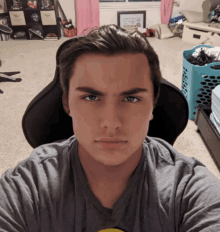 a young man in a gray shirt is sitting in a chair