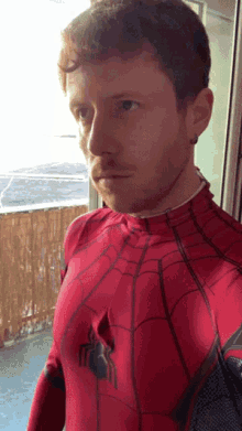 a man in a red spiderman costume looks to the side