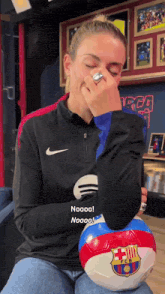 a woman wearing a nike shirt holds a soccer ball