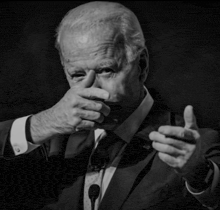a man in a suit and tie is covering his mouth with his hand