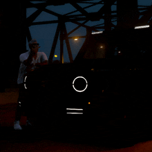 a man is standing in front of a car with a circle on the headlight