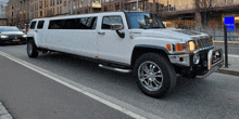 a white hummer limousine is parked on the side of a road