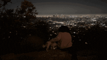 a person sitting on a hill with a dog looking at a city at night with the word shagarita on the bottom