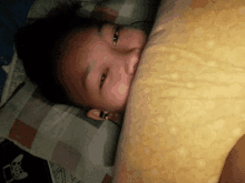 a person is laying on a bed with a yellow pillow