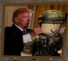 a picture of donald trump holding a medal next to a soldier