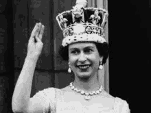 a black and white photo of queen elizabeth wearing a crown and waving .