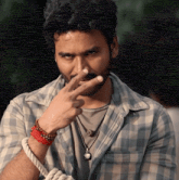 a man wearing a plaid shirt and a necklace with a pendant that says ' a ' on it