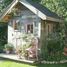 a small wooden shed with pink windows and a pink chair is sitting in the grass .