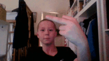 a young boy in a black shirt is making a middle finger gesture