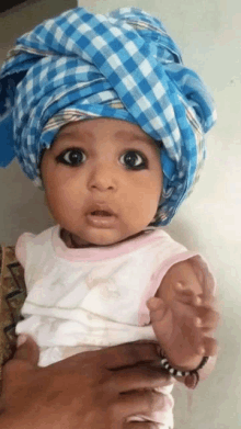 a baby wearing a blue head scarf is being held by a woman .