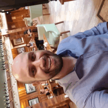 a man with a beard and a blue shirt smiles in a restaurant