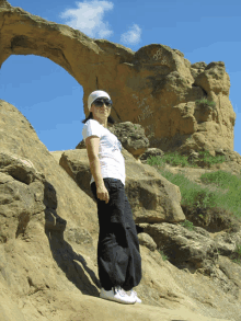 a woman standing in front of a rock formation with graffiti on it that says ' i love you '