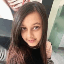 a young girl with long hair is taking a selfie in front of a mirror .