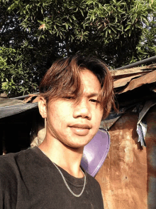 a young man wearing a chain around his neck poses for a photo