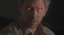 a man with red eyes and a beard looks at the camera