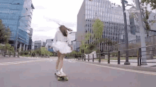 a woman in a white dress is riding a skateboard down a street with a sign that says awesome on it