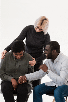 a group of people are sitting in chairs and one of them is holding another woman 's hand