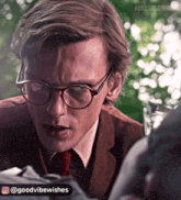 a close up of a man wearing glasses and a brown suit and tie