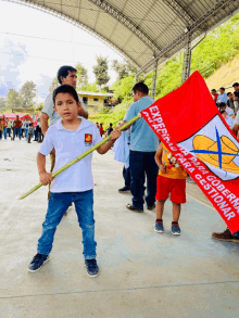 a boy in a white shirt holds a red and white flag that says ' esperanza para gestionar ' on it