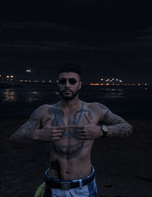 a shirtless man with a skull tattoo on his chest stands in front of a body of water