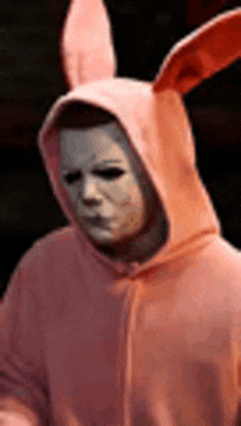 a man wearing a pink hoodie and bunny ears is wearing a mask .