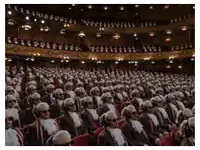 a large group of people are sitting in a theater wearing wigs and sunglasses