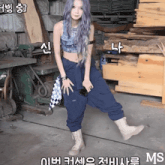 a woman with purple hair is standing in front of a pile of wood and a sign that says ms
