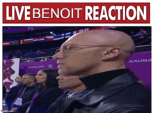 a bald man wearing glasses stands in front of a live benoit reaction banner