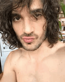 a man with long curly hair and a beard is taking a selfie .