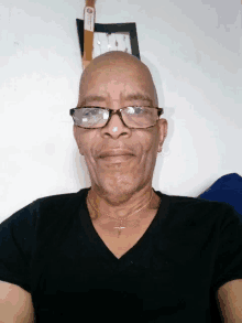 a man wearing glasses and a cross necklace smiles for the camera