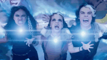 a group of people are standing next to each other with their mouths open in front of a blue light .