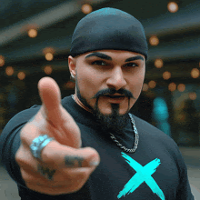 a man with a beard and mustache wearing a black shirt with an x on it