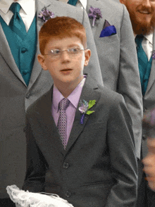 a boy wearing glasses and a purple shirt is holding a wedding pillow