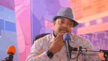 a man sitting in front of a microphone with a hat on