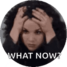 a woman is holding her head in her hands and asking what now .