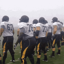 a group of football players are standing on a field and one of them has the number 77 on his jersey