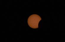 a partial eclipse of the sun with a small dot in the middle